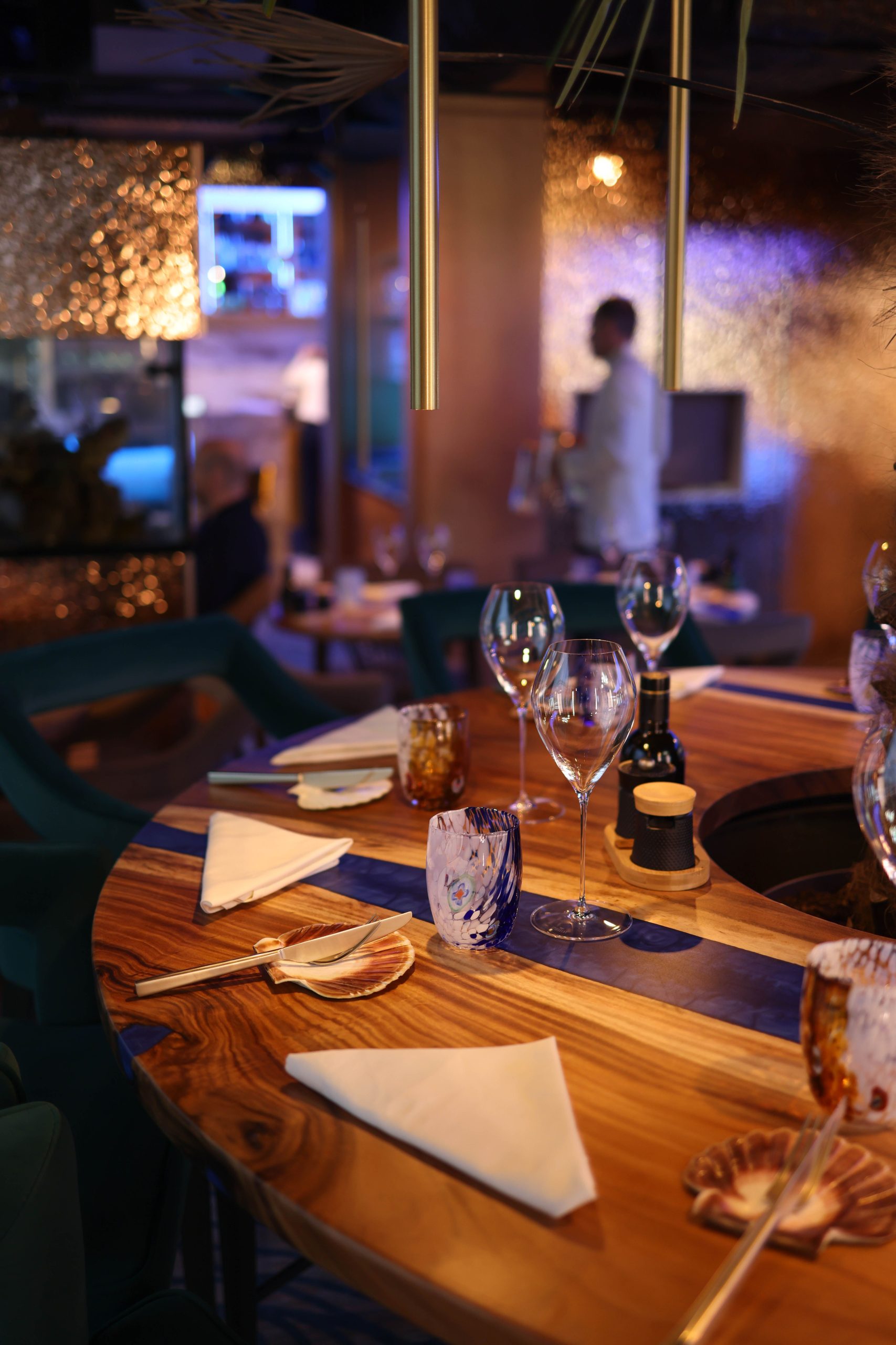 Warmly lit elegant fine dining restaurant with wooden tables set for dinner