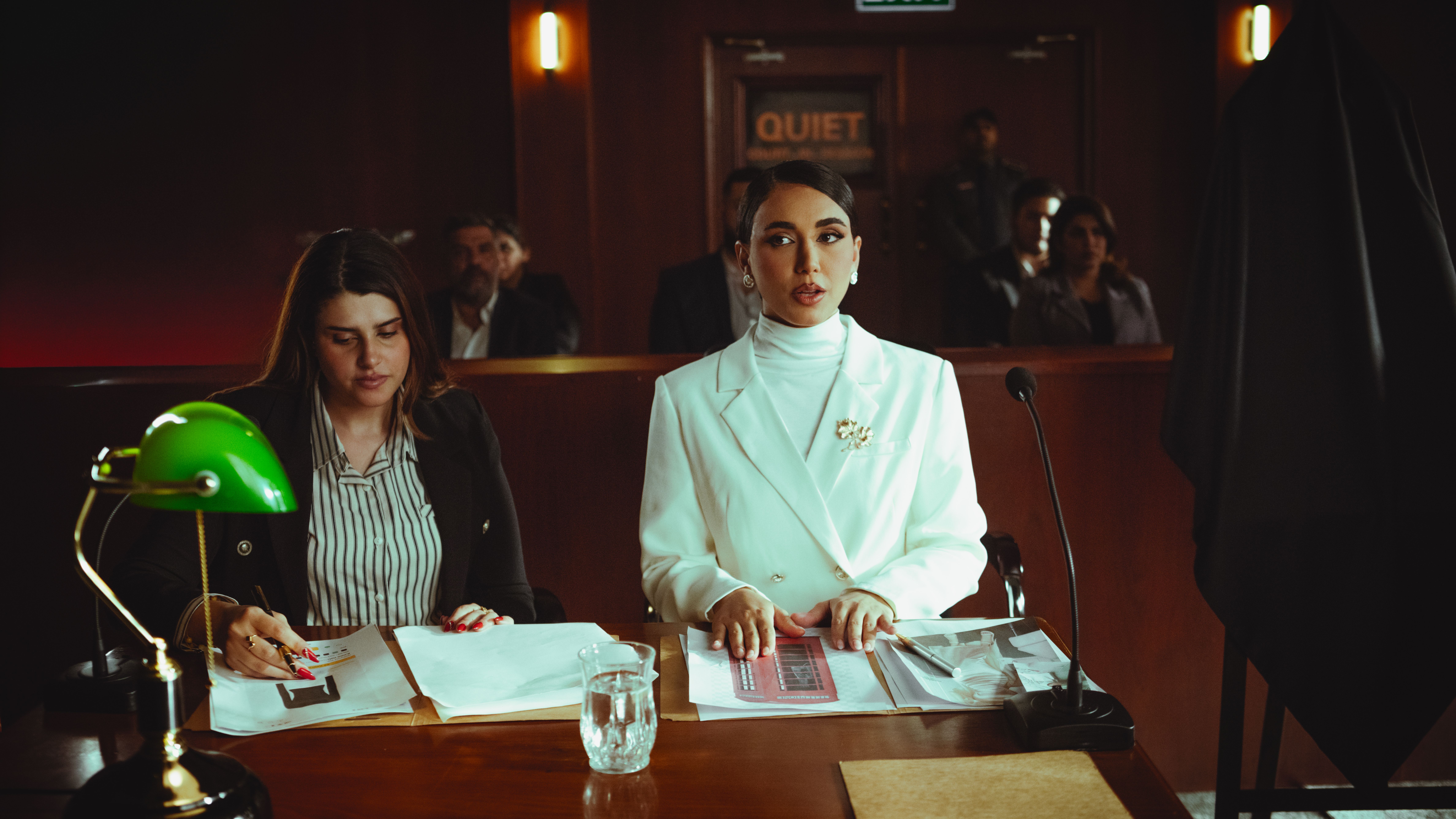 Two female lawyers reviewing legal documents in a courtroom during large-scale litigation proceedings