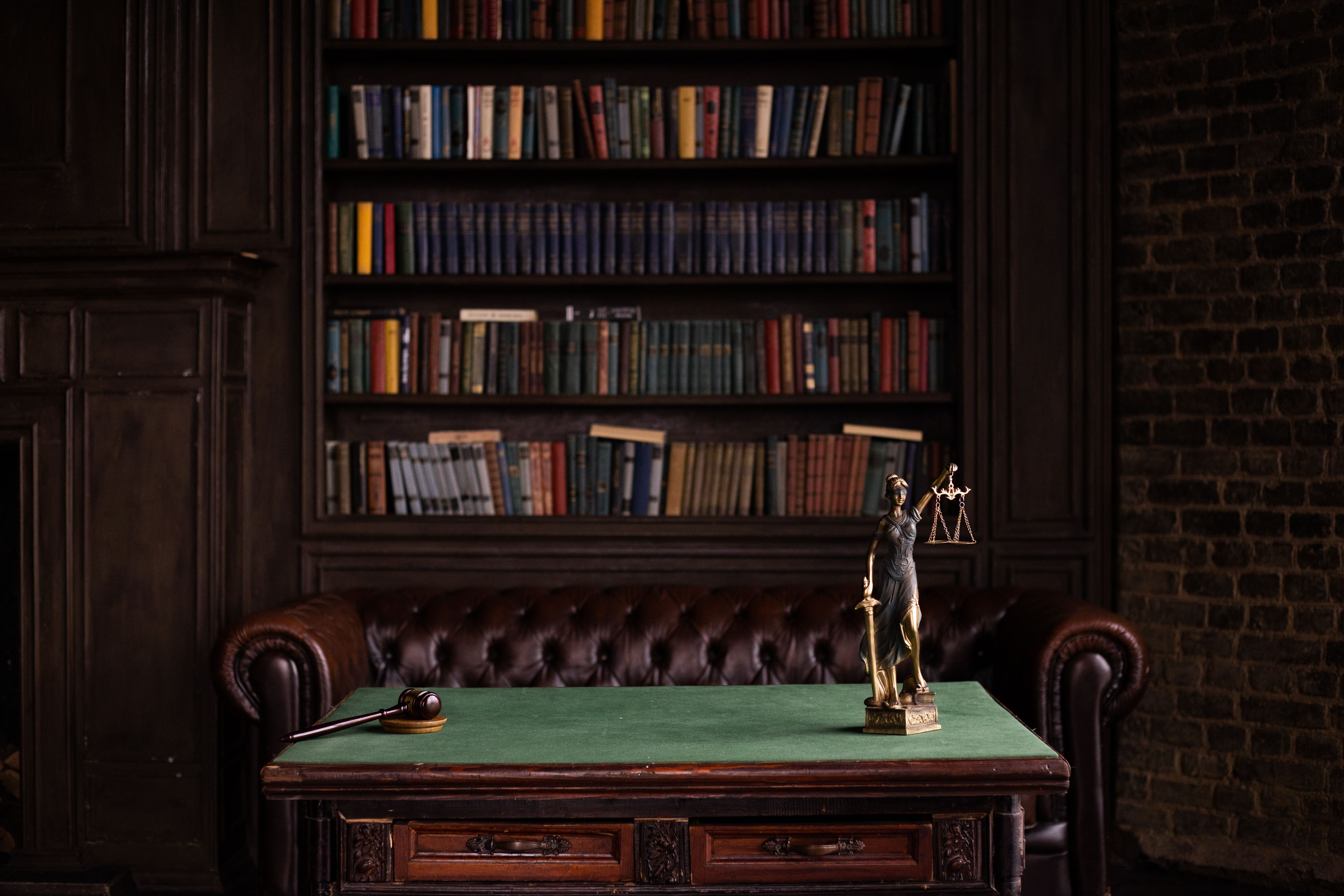 Study room with law books, a gavel, and a Lady Justice figurine on a green table