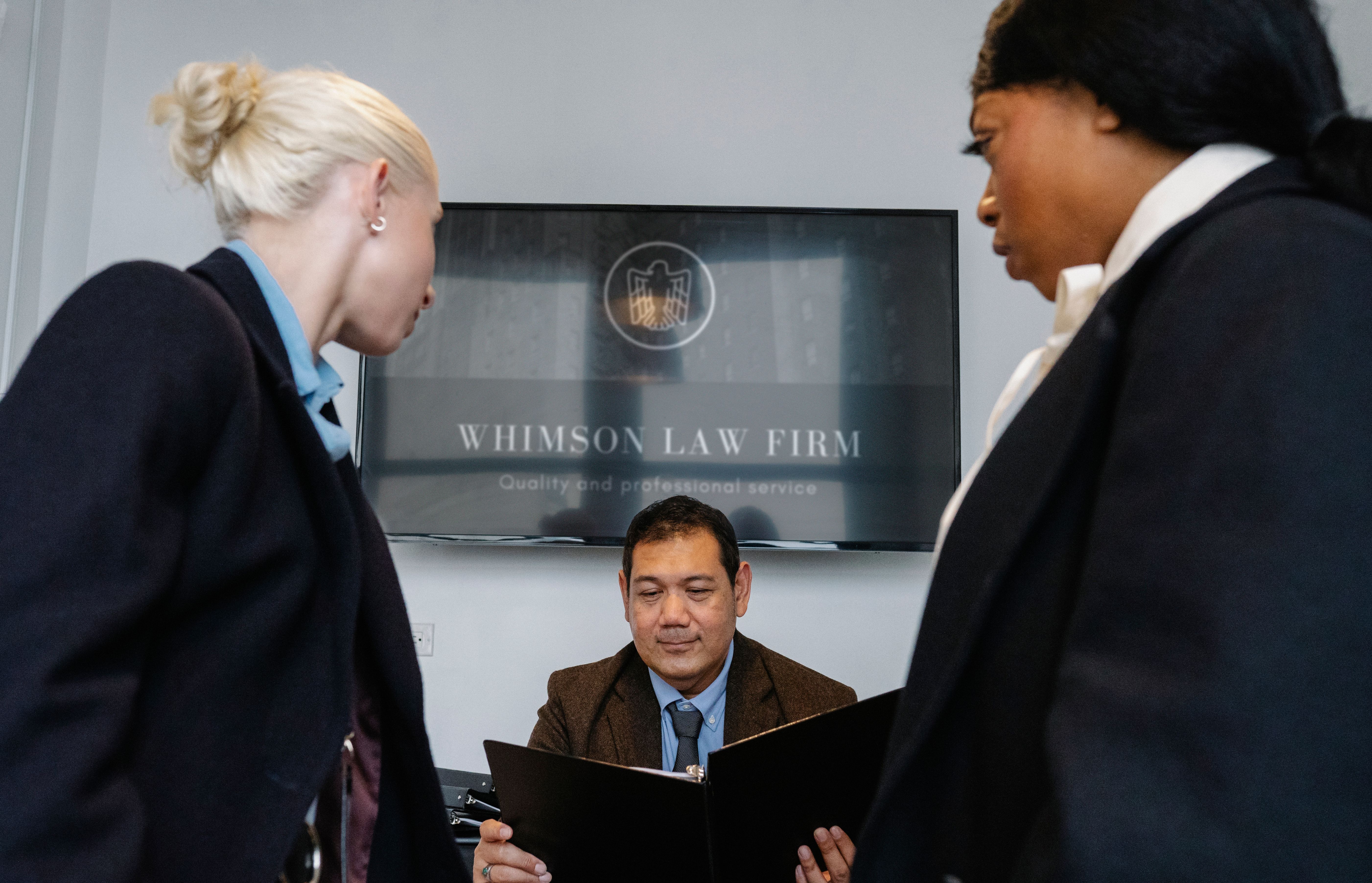 Diverse legal team gathered in a law firm conference room discussing contract details and litigation strategy